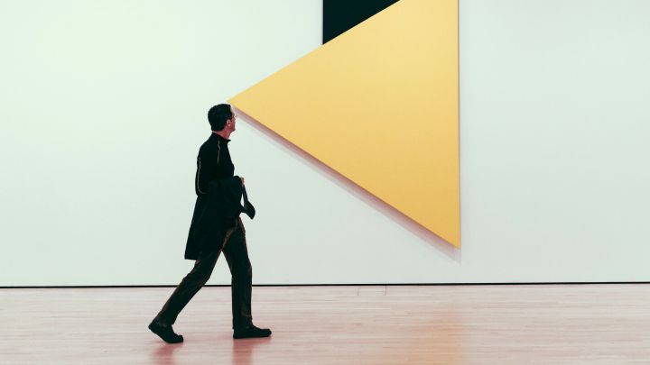 Ein Mann in einer Kunstgalerie vor einem großen Dreieck (wie ein Blickfeld)