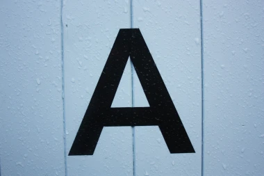 Ein großes aufgeklebtes A auf einer nassen Fassade