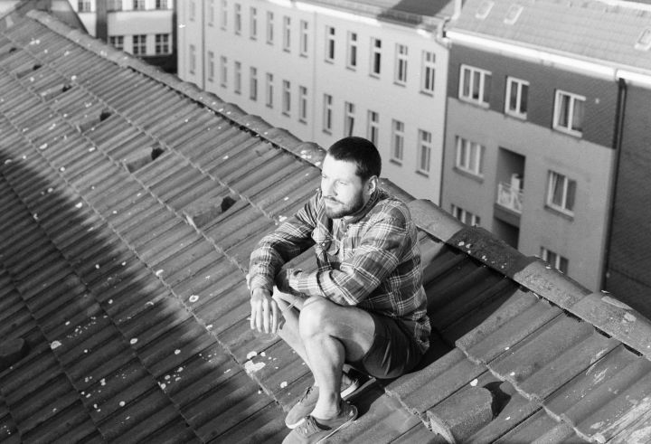 Ein Mensch sitzt auf einem hohen Häuserdach in Berlin
