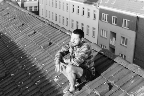 Ein junger Mann sitzt auf dem Dach eines hohen Gebäudes